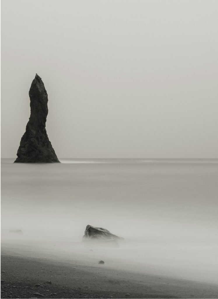 imagen en blanco y negro de una roca enmedio del mar